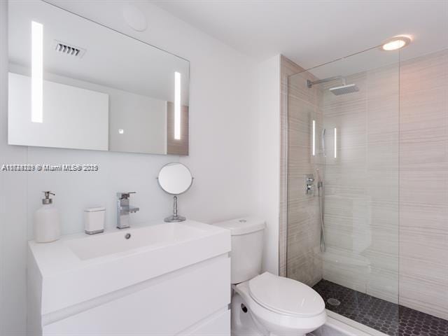 bathroom featuring vanity, toilet, and a tile shower