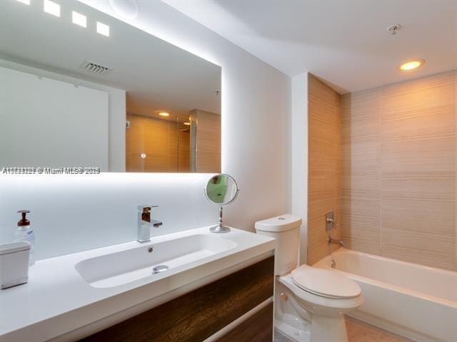 full bathroom featuring vanity, toilet, and tiled shower / bath combo