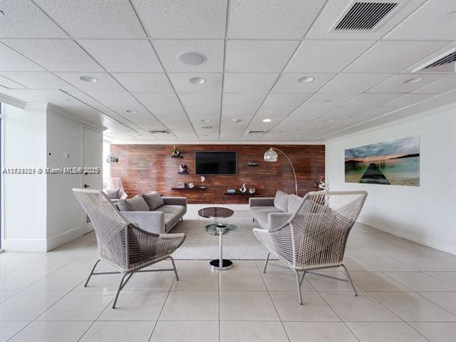 tiled living room with a paneled ceiling and wood walls