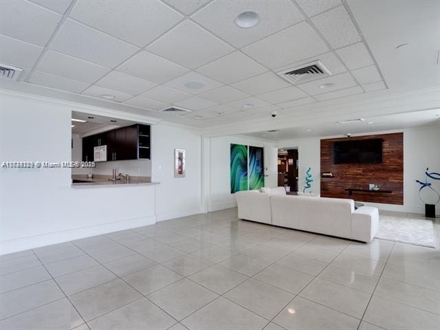 unfurnished living room with a drop ceiling and light tile patterned flooring