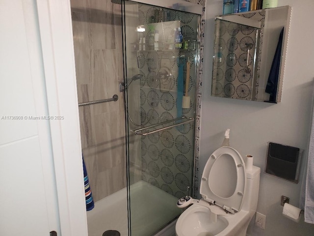 bathroom featuring toilet and a shower with shower door