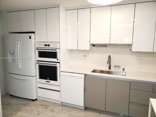 kitchen featuring sink, white cabinetry, tasteful backsplash, light tile patterned floors, and white appliances