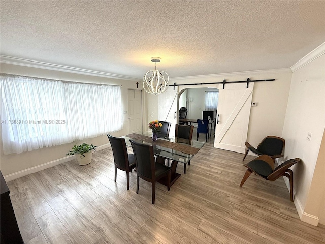 dining area with crown molding, a barn door, and hardwood / wood-style floors