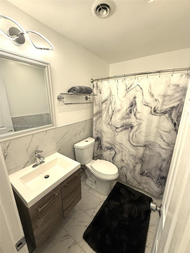 bathroom with vanity, tile walls, walk in shower, and toilet