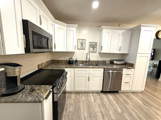 kitchen featuring sink, white cabinets, dark stone counters, light hardwood / wood-style floors, and stainless steel appliances