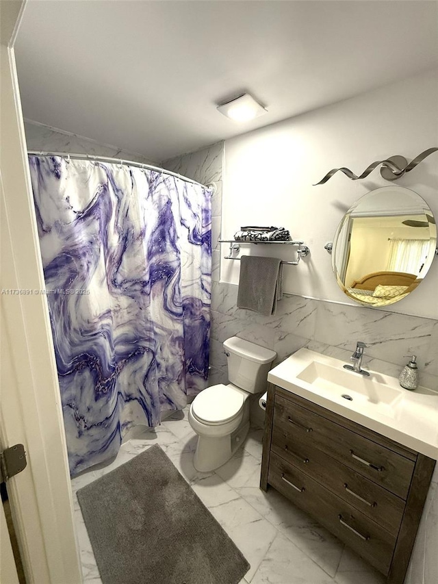 bathroom with vanity, curtained shower, tile walls, and toilet