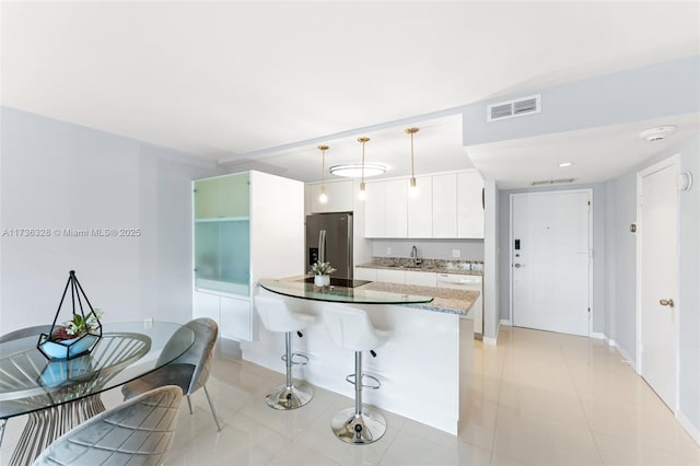 155 Ocean Lane Dr Unit 407, Key Biscayne, FL 33149 - kitchen with stainless steel refrigerator with ice dispenser, a breakfast bar, pendant lighting, white cabinets, and light tile patterned floors