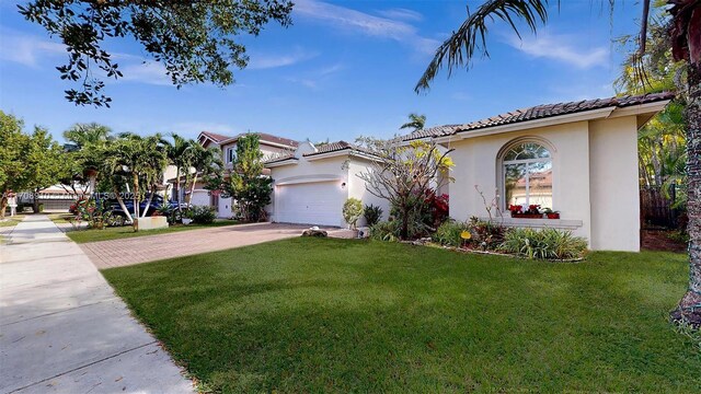 mediterranean / spanish house featuring a garage and a front lawn