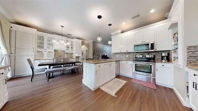 kitchen featuring appliances with stainless steel finishes, white cabinetry, hanging light fixtures, kitchen peninsula, and light stone countertops