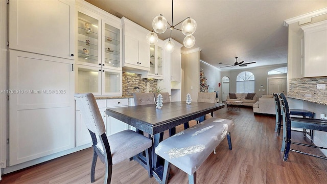 dining space featuring hardwood / wood-style floors, ceiling fan with notable chandelier, and ornamental molding