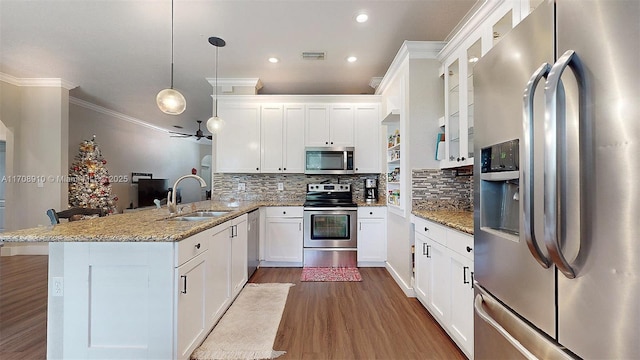 kitchen with appliances with stainless steel finishes, sink, white cabinets, hanging light fixtures, and kitchen peninsula