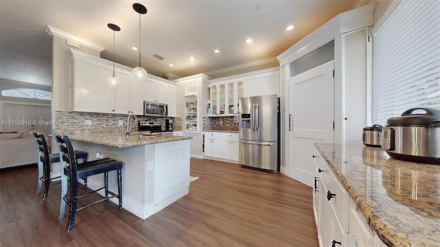 kitchen featuring a breakfast bar, white cabinetry, appliances with stainless steel finishes, pendant lighting, and light stone countertops