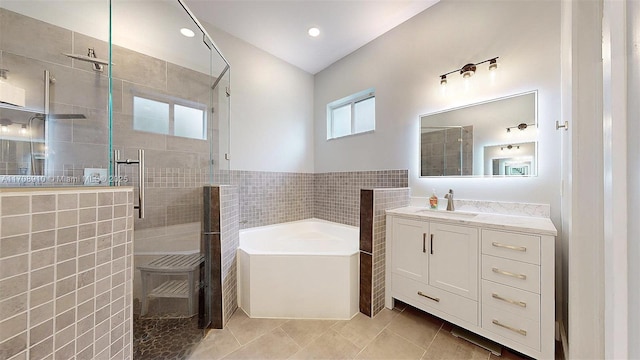 bathroom featuring vanity, plus walk in shower, tile patterned flooring, and tile walls