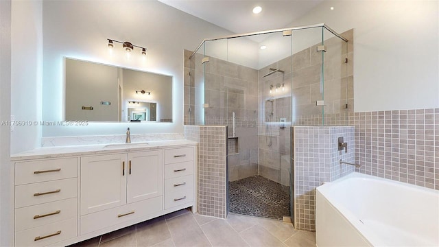 bathroom with tile walls, vanity, tile patterned flooring, and plus walk in shower