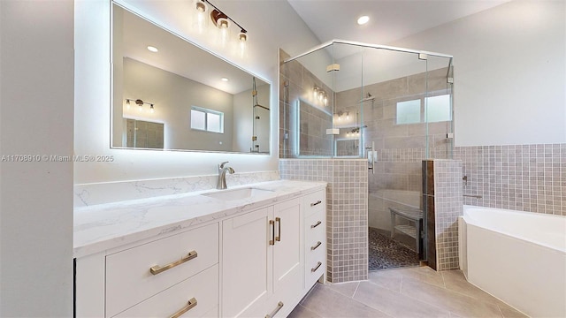 bathroom with vanity, plus walk in shower, tile patterned flooring, and tile walls