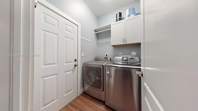 laundry room with cabinets, washing machine and dryer, and wood-type flooring