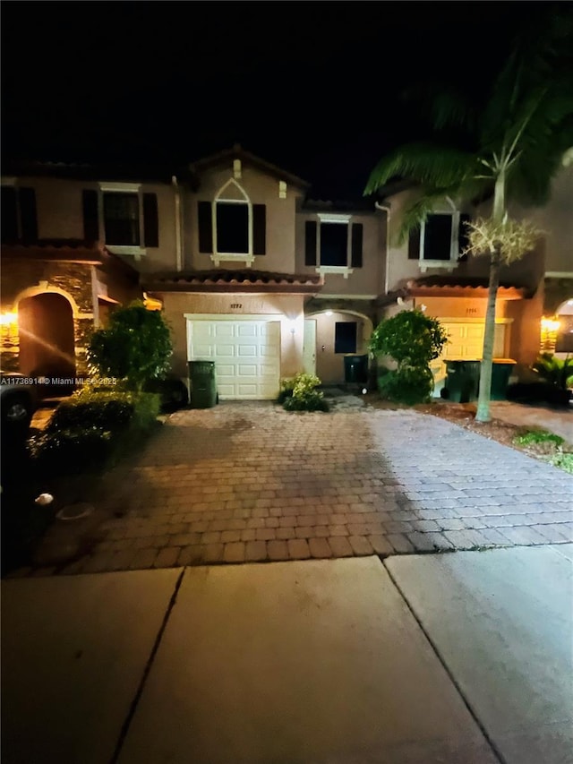 mediterranean / spanish-style house with decorative driveway, an attached garage, and stucco siding