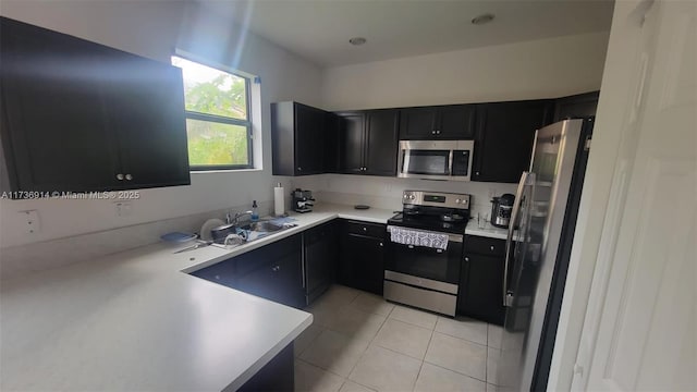 kitchen featuring light tile patterned floors, stainless steel appliances, dark cabinetry, and light countertops