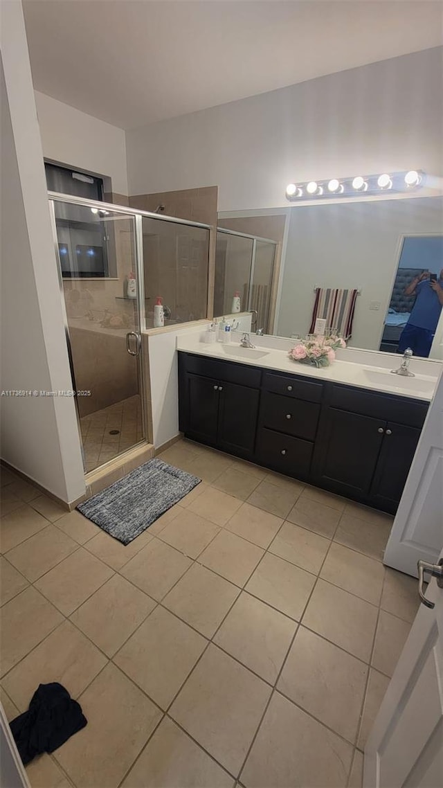 full bathroom with double vanity, a stall shower, tile patterned flooring, and a sink