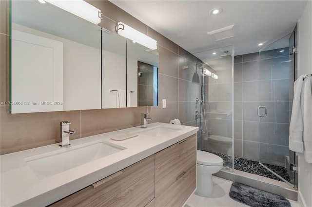 bathroom featuring tile walls, backsplash, vanity, a shower with shower door, and toilet