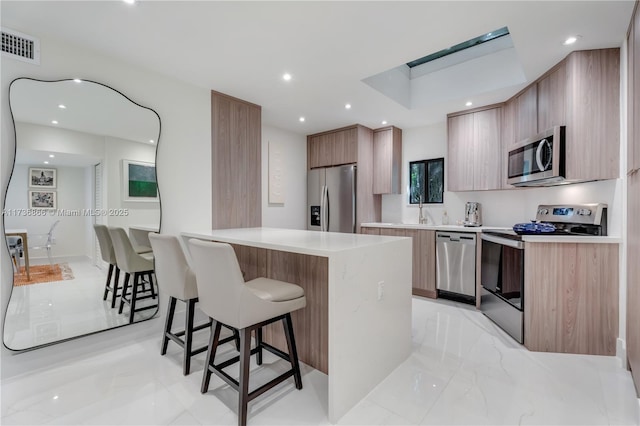 kitchen featuring appliances with stainless steel finishes, a center island, and a breakfast bar