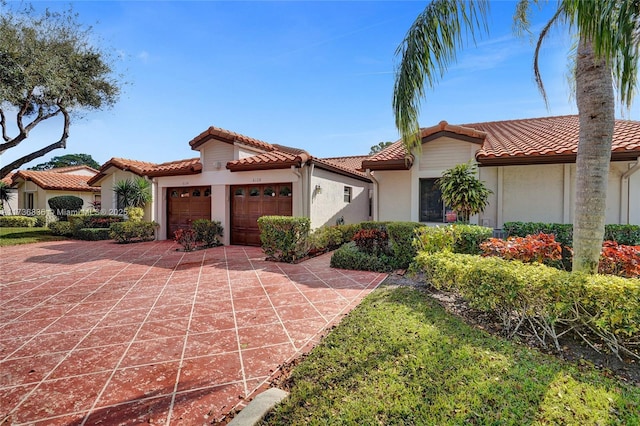 mediterranean / spanish-style home featuring a garage, a tile roof, concrete driveway, and stucco siding