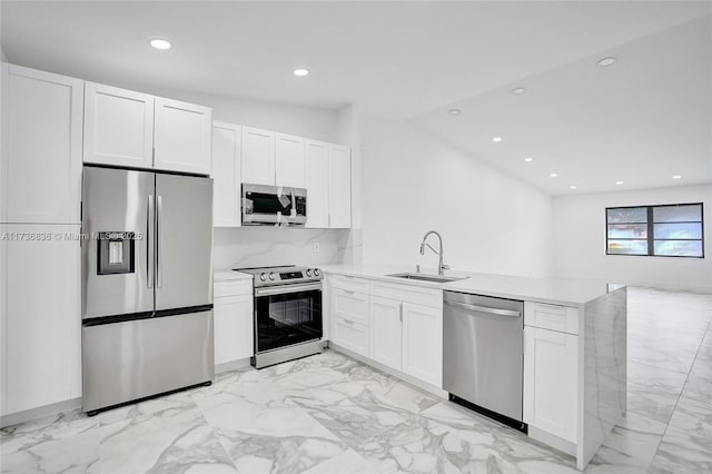 kitchen featuring a peninsula, appliances with stainless steel finishes, light countertops, and a sink