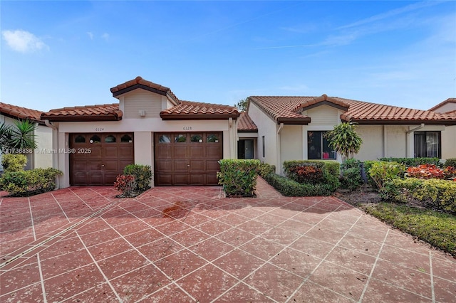 mediterranean / spanish home with a tiled roof, an attached garage, and stucco siding