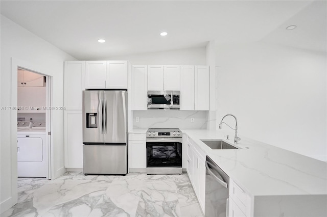 kitchen with light stone countertops, white cabinetry, stainless steel appliances, and washing machine and clothes dryer