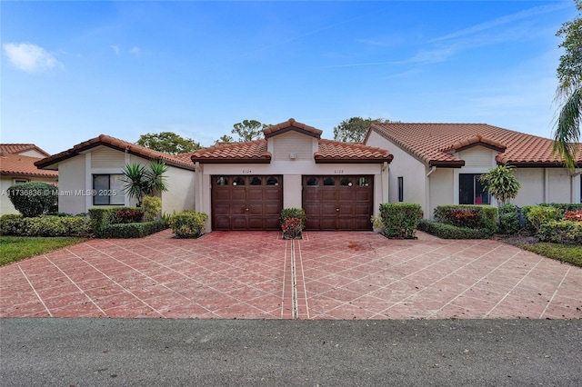 mediterranean / spanish-style house featuring a garage, concrete driveway, a tile roof, and stucco siding