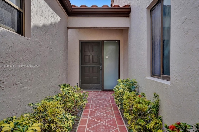 entrance to property with a tile roof and stucco siding