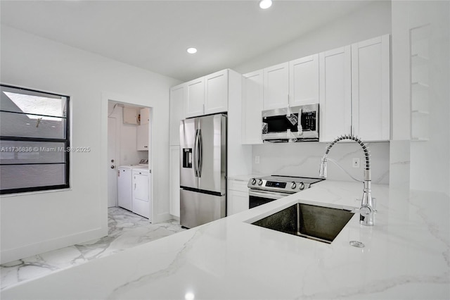 kitchen with stainless steel appliances, a sink, marble finish floor, independent washer and dryer, and light stone countertops