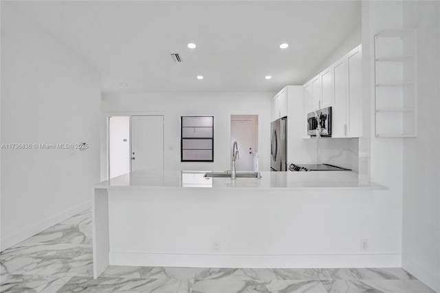 kitchen featuring stainless steel appliances, visible vents, light countertops, a sink, and a peninsula