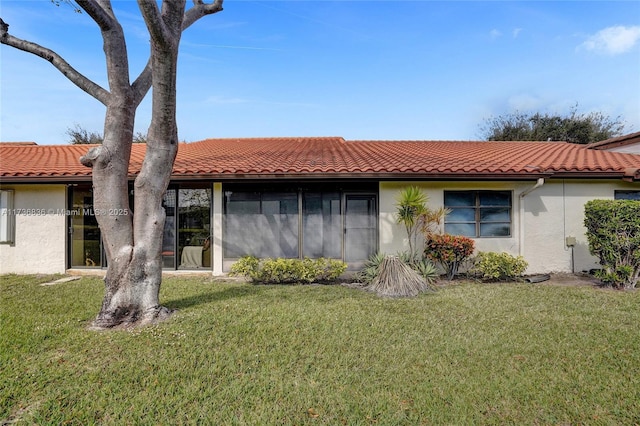 view of front facade with a yard, a tiled roof, and stucco siding