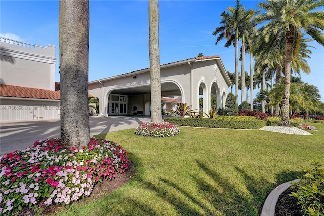 view of front facade featuring driveway, a yard, and stucco siding