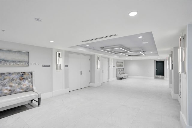 interior space with baseboards, a raised ceiling, and recessed lighting