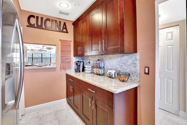 kitchen featuring light stone counters, stainless steel fridge, and decorative backsplash