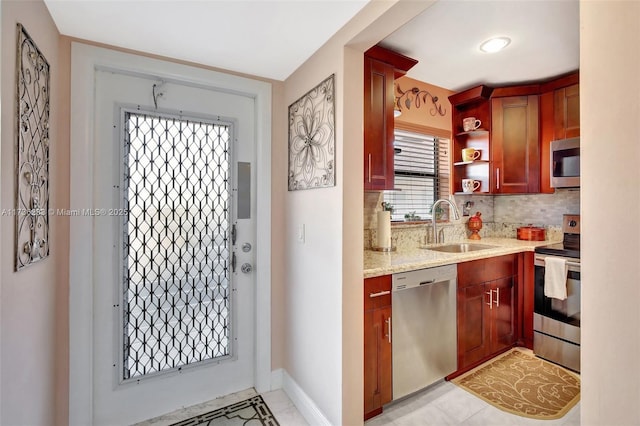 kitchen with appliances with stainless steel finishes, sink, light stone counters, and decorative backsplash