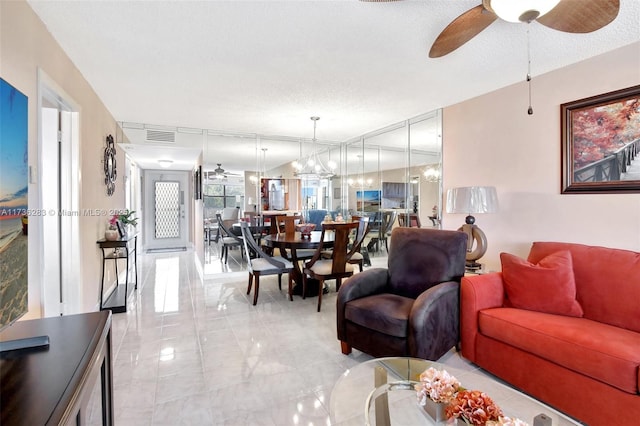 living room featuring ceiling fan with notable chandelier and a textured ceiling