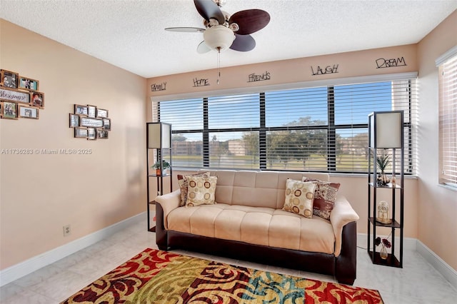 living room with ceiling fan, a wealth of natural light, and a textured ceiling