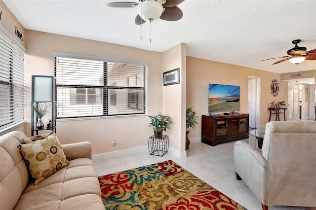 living room with a textured ceiling, ceiling fan, and light tile patterned flooring