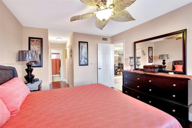 bedroom with a textured ceiling, ensuite bath, and ceiling fan