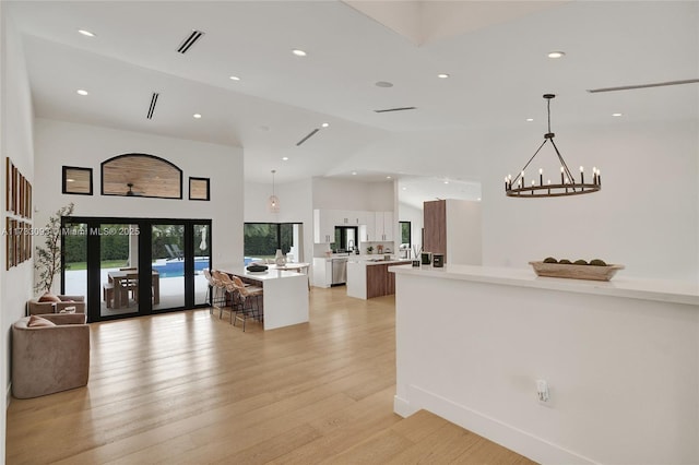 kitchen featuring a kitchen island, high vaulted ceiling, french doors, hanging light fixtures, and light hardwood / wood-style flooring