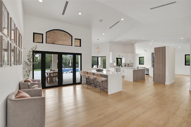 kitchen with french doors, a breakfast bar, a center island, pendant lighting, and white cabinets