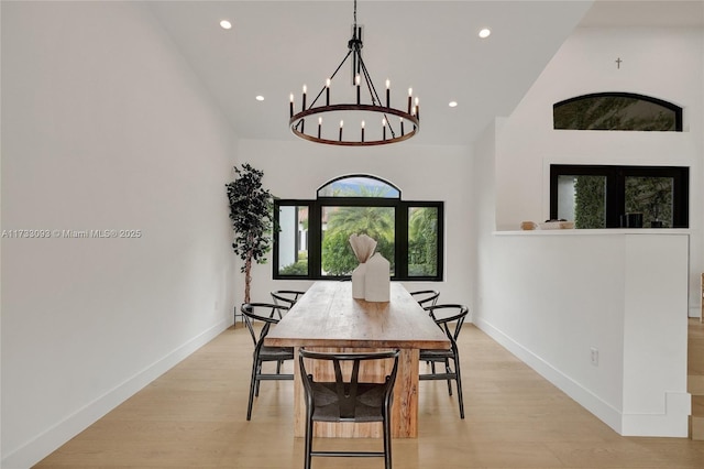 dining room with a notable chandelier, high vaulted ceiling, and light wood-type flooring