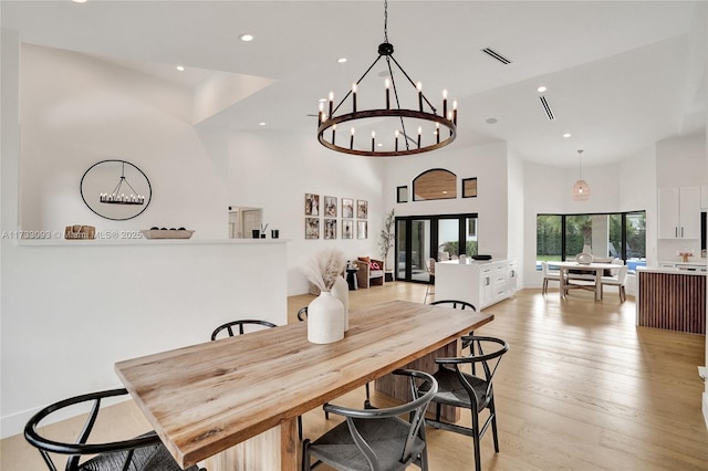 dining space featuring a towering ceiling and light hardwood / wood-style floors