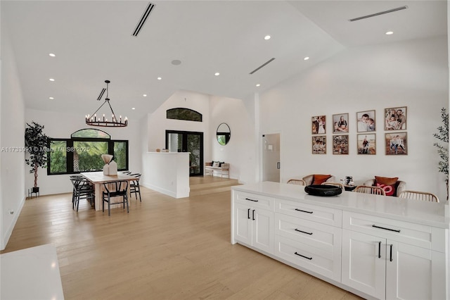 kitchen featuring pendant lighting, white cabinetry, high vaulted ceiling, a notable chandelier, and light hardwood / wood-style floors