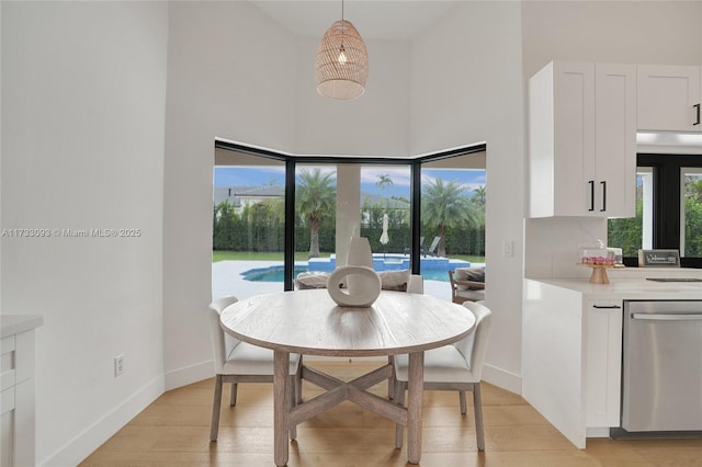 dining area featuring light hardwood / wood-style floors and a high ceiling