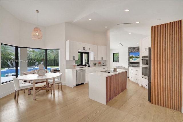 kitchen featuring stainless steel appliances, a center island, pendant lighting, and white cabinets