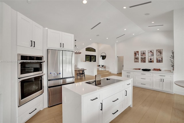 kitchen featuring white cabinetry, appliances with stainless steel finishes, a center island, and light wood-type flooring